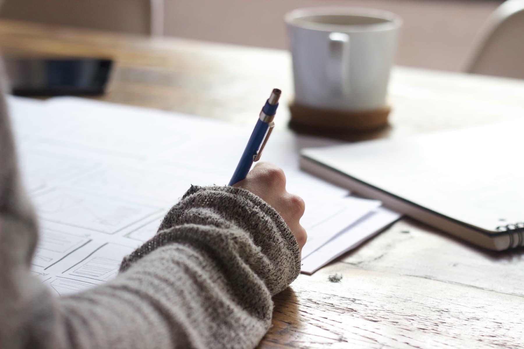 Writing workspace with notebook, coffee, and laptop